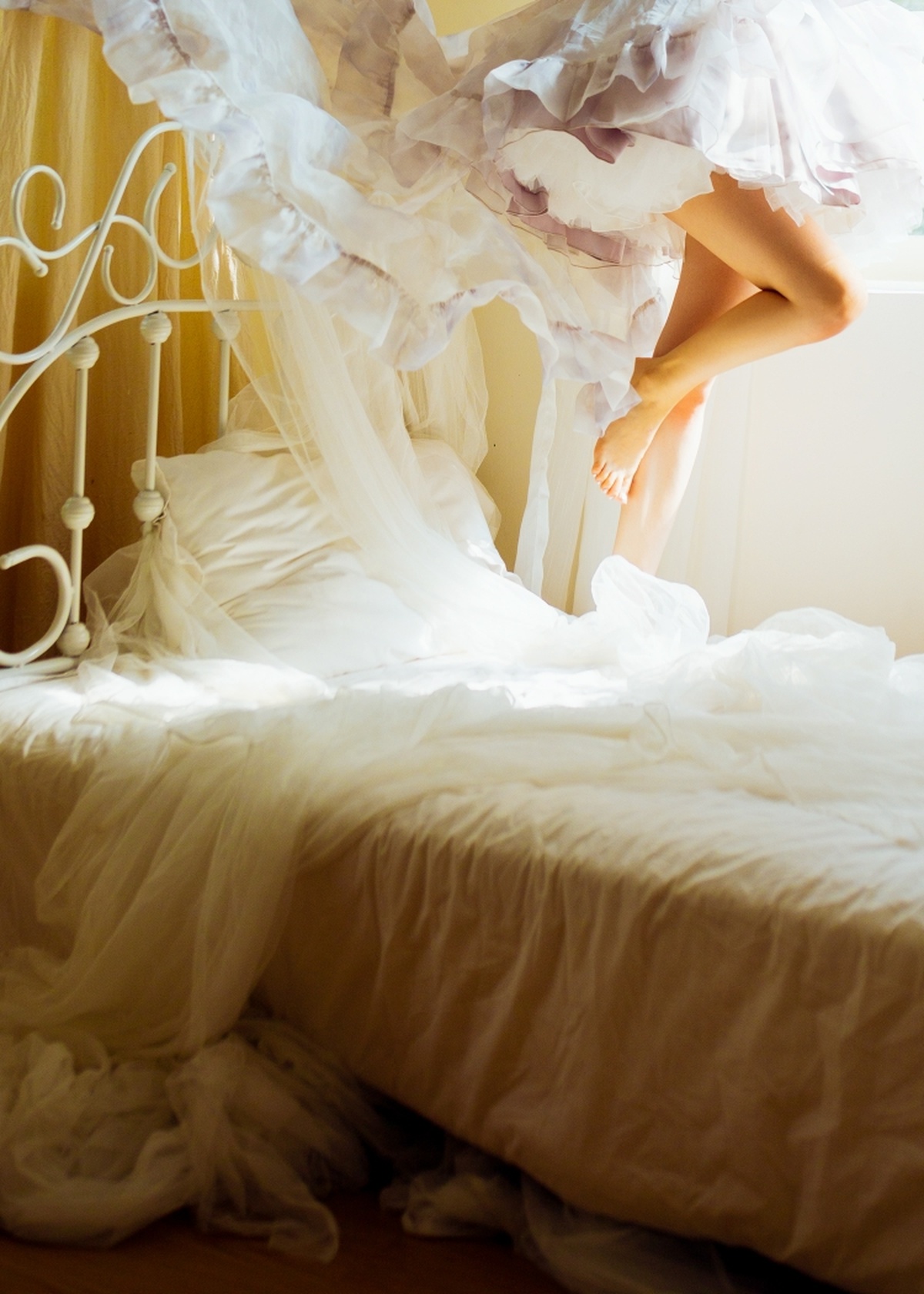 一个穿着白色连衣裙的年轻女子在床上跳跃