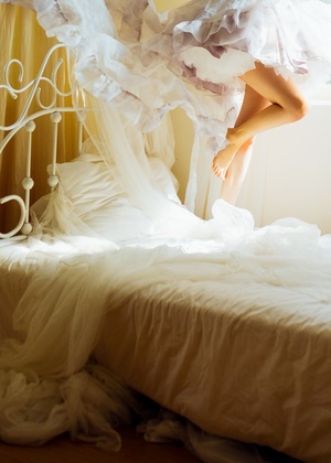 一个穿着白色连衣裙的年轻女子在床上跳跃