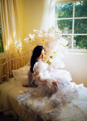 一个穿着白色婚纱的年轻女子坐在床上