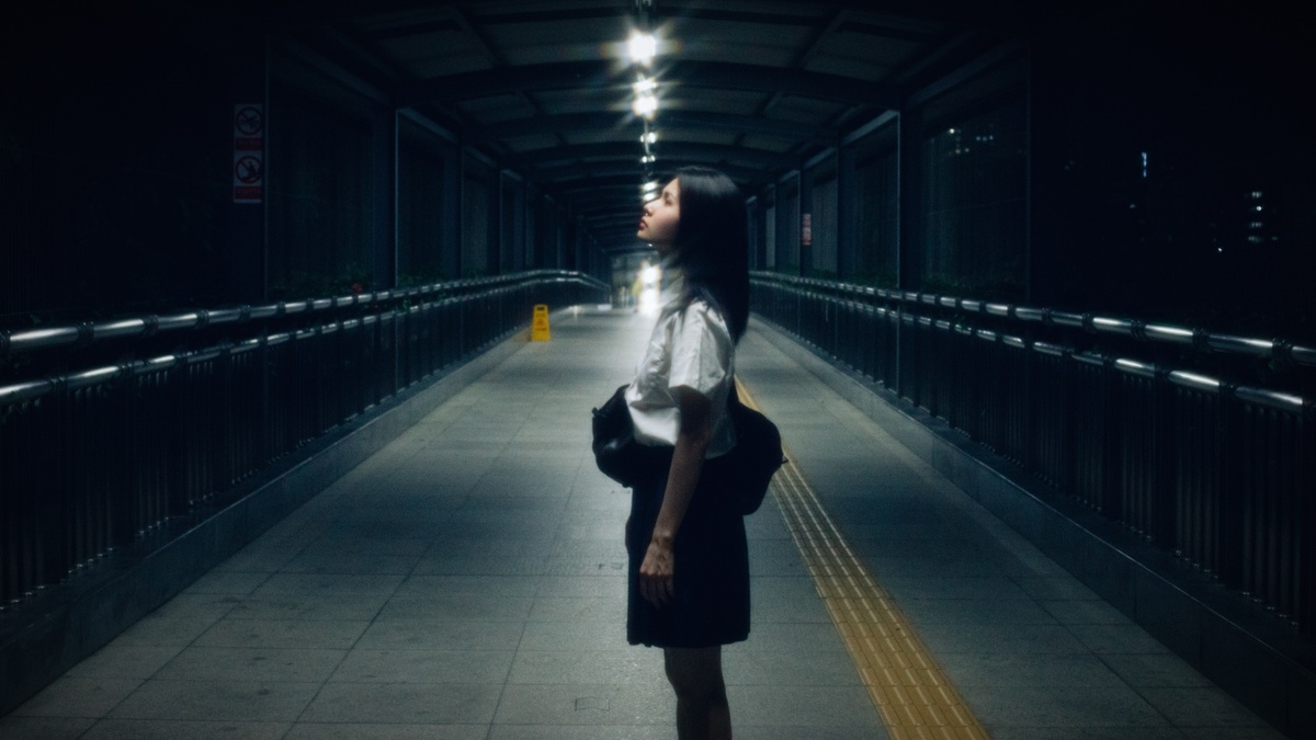 一个提着行李箱的女人站在夜晚的黑暗隧道里