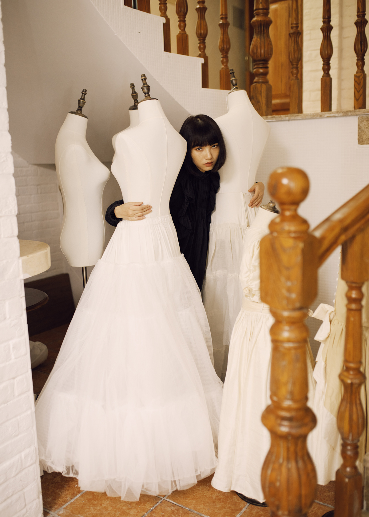一位穿着白色婚纱的女人站在楼梯旁边 旁边有模特。