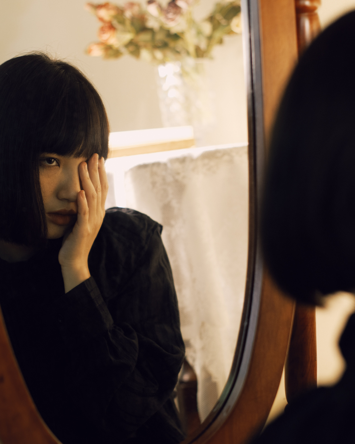 一个年轻女子坐在镜子前看着自己的倒影