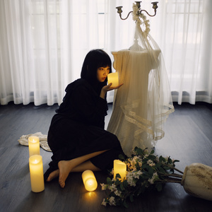 一个年轻女子坐在地板上 周围环绕着点燃的蜡烛和鲜花 在一个房间里。