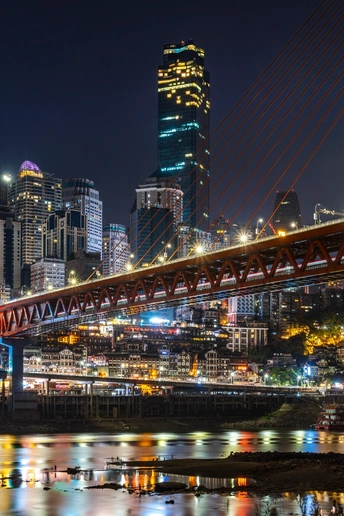 在高高的城市天际线前 水面上的一座桥在夜晚亮了起来