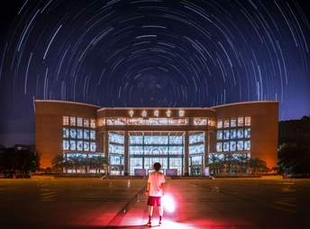 站在被夜晚星空照亮的大楼前的男孩