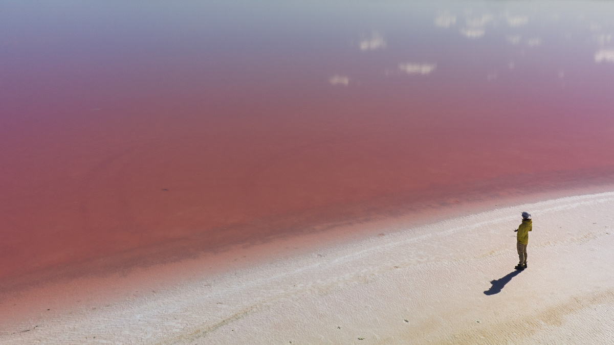 一个人在红水和粉沙海滩上行走