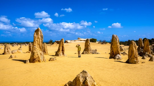 一片沙漠的风景 一个人站在前景中的沙子和岩石上。