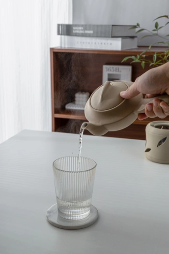 一个人在桌子上戴着帽子往杯子里倒水