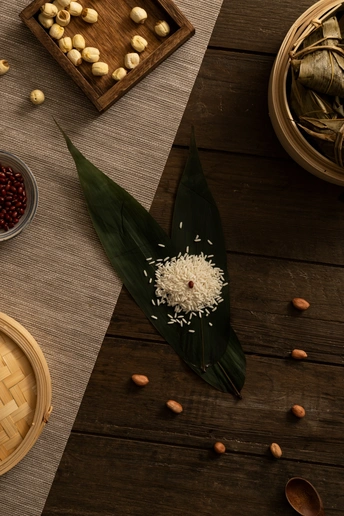 一个木制桌子 上面放着一盘食物 一个白米饭碗 一束花和一些豆子。