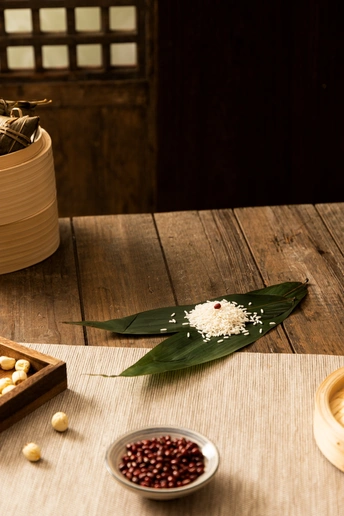 一个木制桌子 上面放着一盘食物、一个小碗的豆子和一束花。