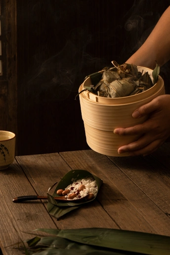 一个人拿着一个碗和筷子在木桌上放着一杯茶