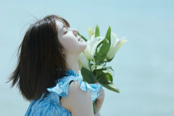 一位身穿蓝色连衣裙的年轻女子手里拿着一束白色百合花
