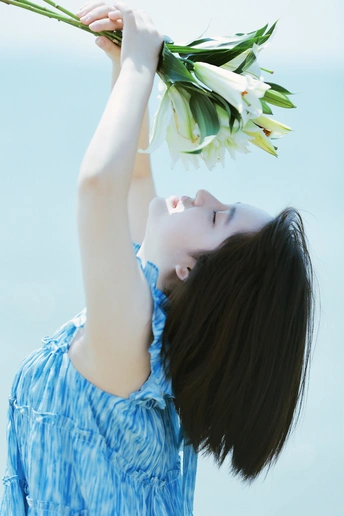 一位身穿蓝色连衣裙的年轻女子头顶一束白花