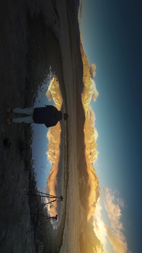 一个人站在海滩上 手里拿着冲浪板 天空中有一只风筝的倒影。