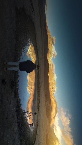 一个人站在海滩上 手里拿着冲浪板 天空中有一只风筝的倒影。