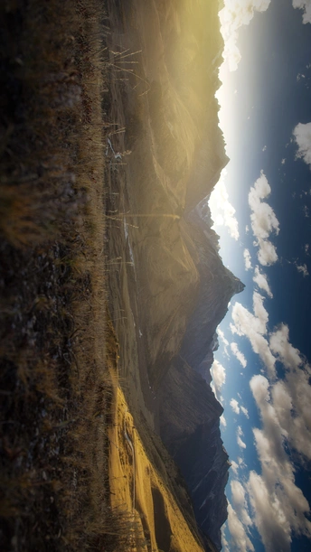 阳光穿过云层 照耀在峡谷中 背景是山脉。
