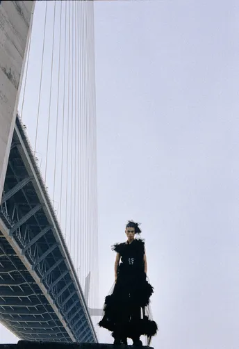 站在桥上的一名男子旁边是一名穿着裙子的女子