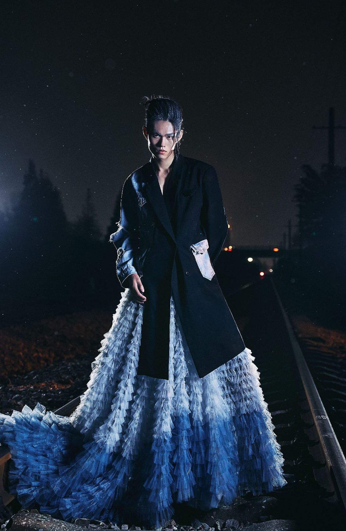 穿着蓝色连衣裙和外套的模特子在夜晚的铁轨上