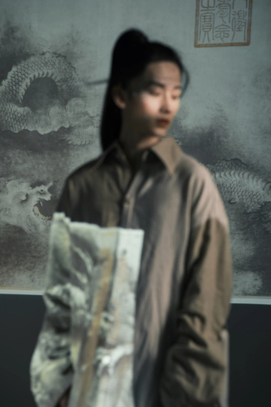一个男人拿着一张女人的照片 站在一幅画前