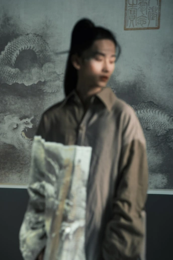 一个男人拿着一张女人的照片 站在一幅画前