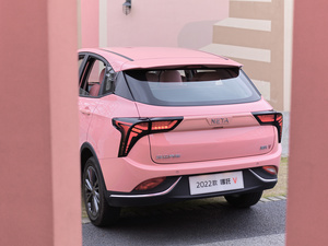 一个小粉红色汽车停在粉红色建筑前面