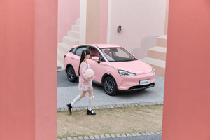 一张小女孩走过一辆粉红色汽车的照片