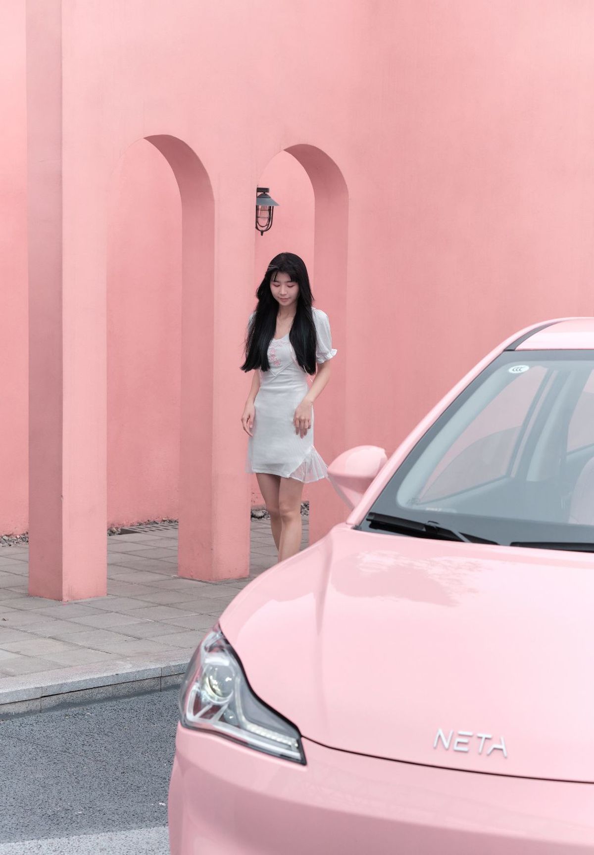 白色上衣女性站在粉色汽车旁边
