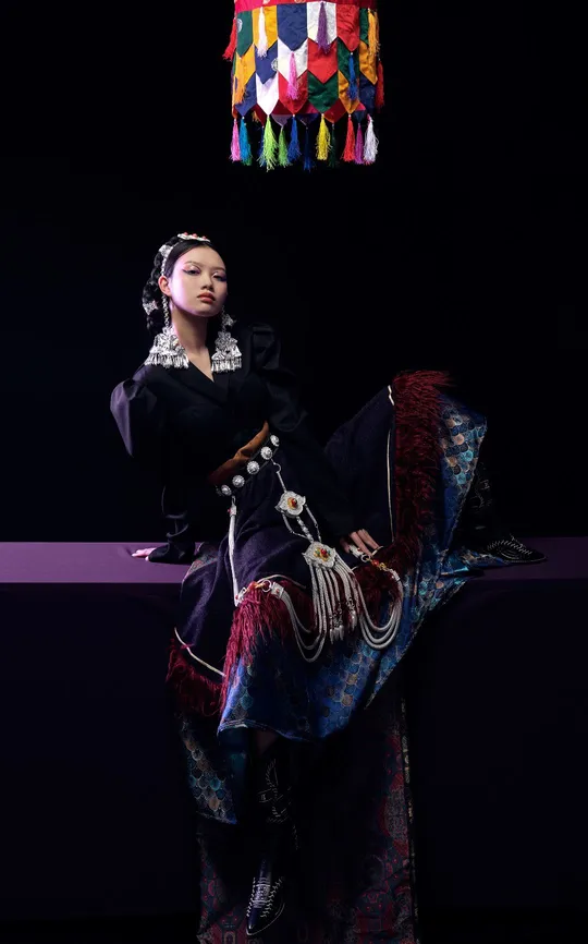 一位穿着传统服装的女性在表演期间坐在一个多彩椅子上。