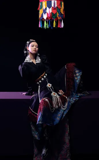 一位穿着传统服装的女性在表演期间坐在一个多彩椅子上。