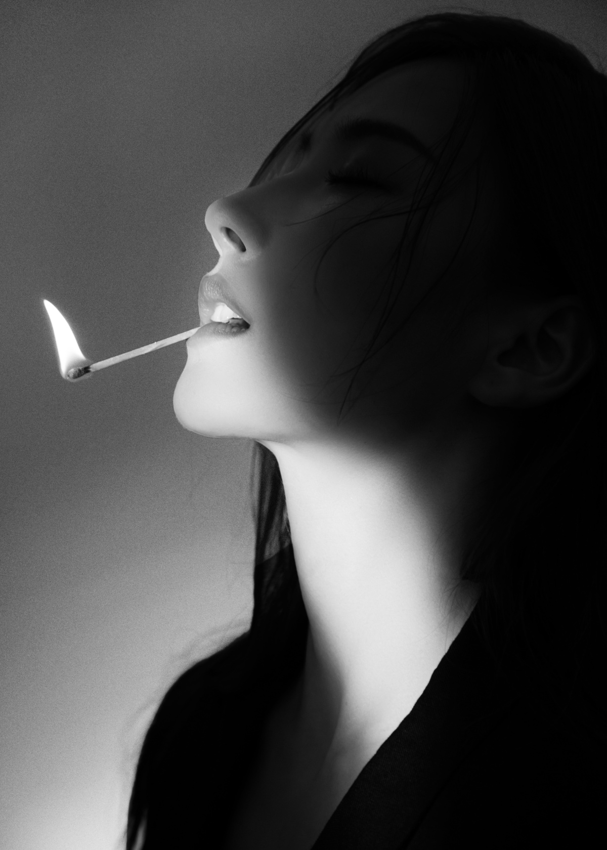 一位女士嘴里含着火柴抽烟的黑白色照片