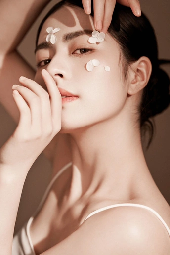 一个美丽的年轻女子脸上和手上涂着白色的妆容 眼睛下面有眼影。
