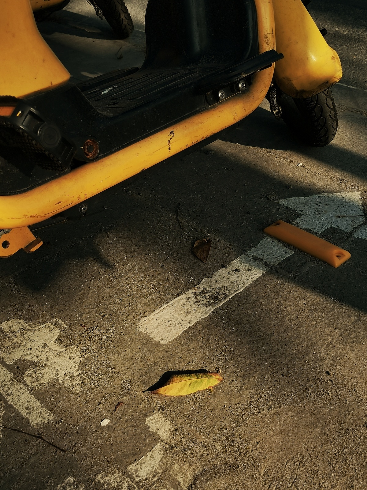 一辆黄色轻便摩托车停在街上 路边放着一根香蕉