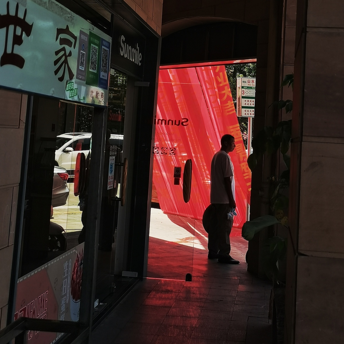 一名男子走在门上有红墙的商店前的人行道上