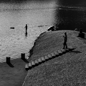 一名男子站在水体附近的台阶上 而一名男孩正在钓鱼