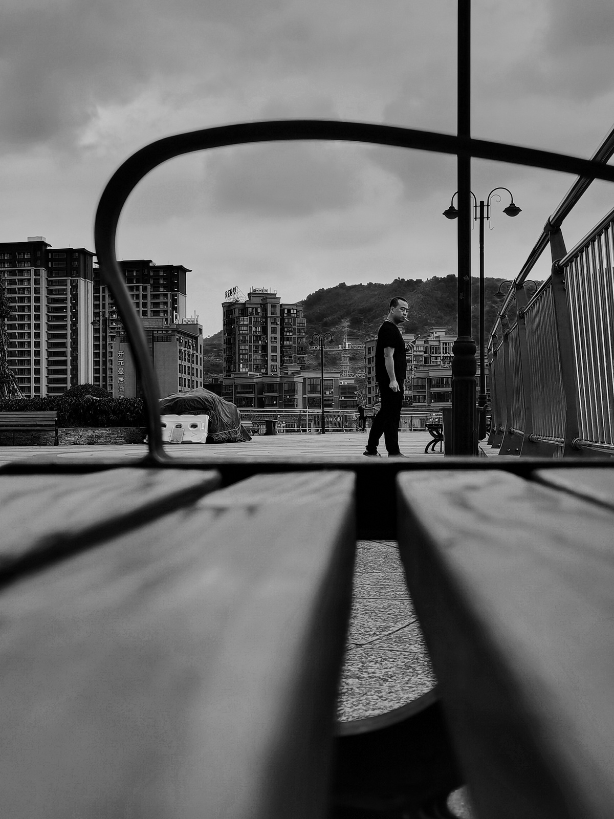一个人走在木凳附近的桥上 背景是一座城市