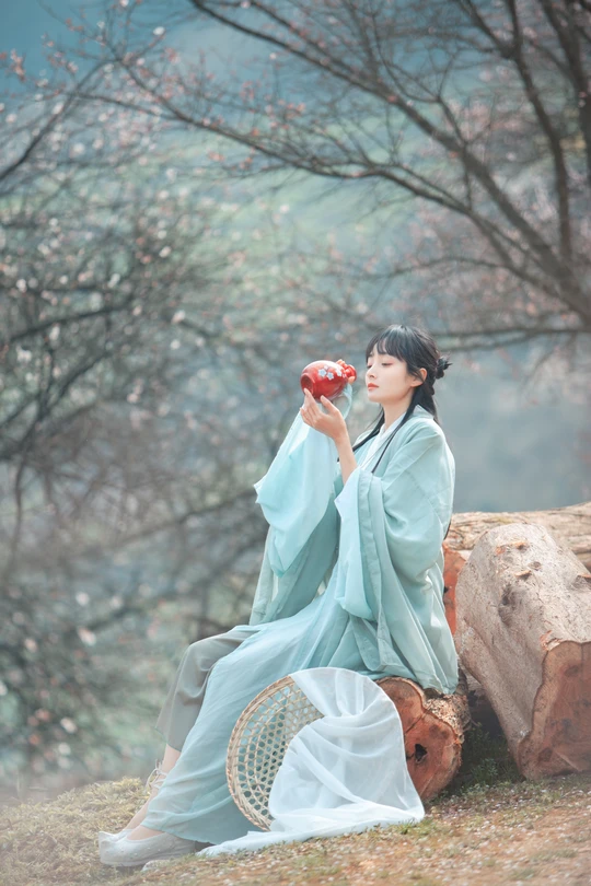 一位穿着蓝色和服的女性正在喝杯子里的东西。