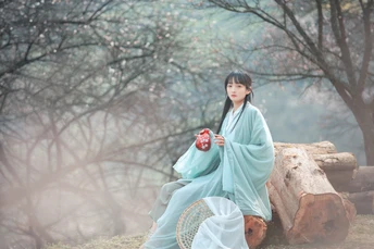 一位穿着蓝色和服的女孩坐在木头上喝茶