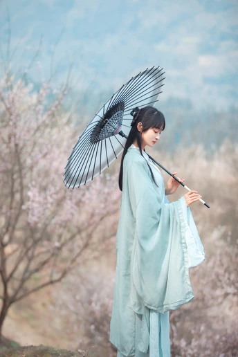 一位穿着传统蓝色和服的年轻女子拿着雨伞