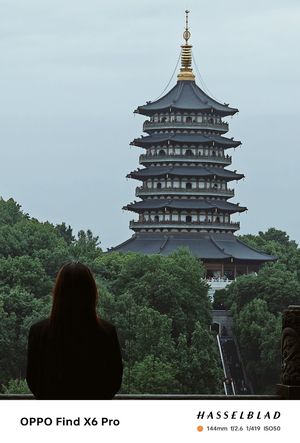 一位女子站在佛塔前 眺望着远方城市中的塔楼。