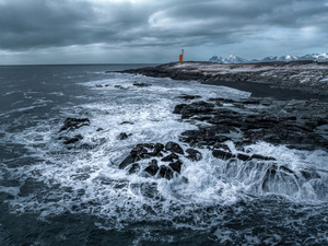 乌云密布的海岸边 波涛汹涌 岩石上矗立着一座灯塔 位于大洋中央。