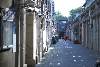 一条狭窄的巷子 有人行走 有人骑自行车在人行道上。