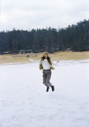 一位年轻女子在雪地中奔跑 小女孩在空中放飞风筝。