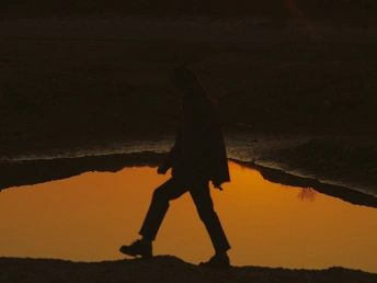 夕阳下漫步在海滩上的男人的剪影