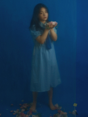 一个小女孩穿着蓝色裙子 手里拿着玫瑰花 贴在蓝色墙壁上。
