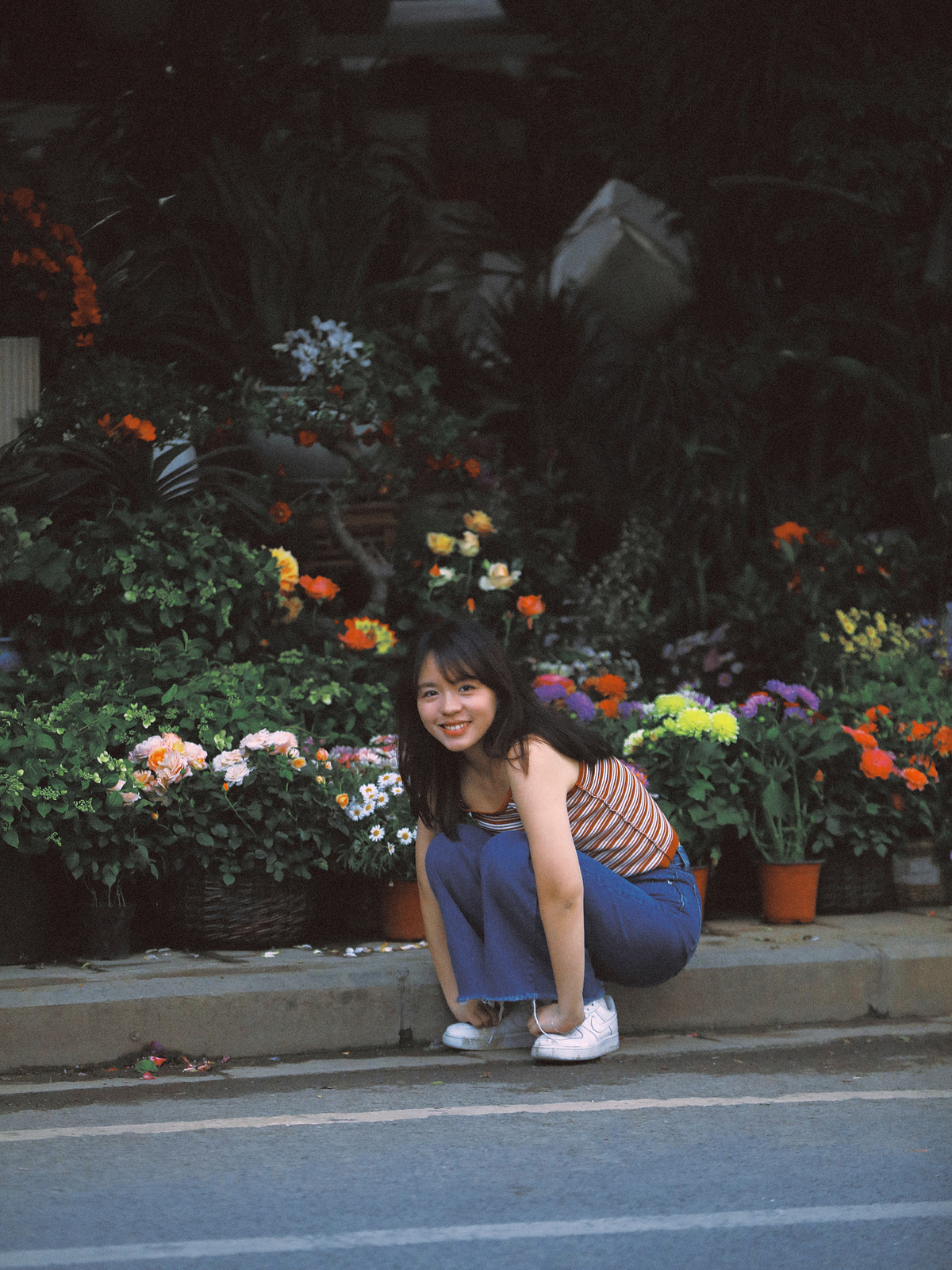 一位年轻女子跪在花店前的人行道上 一个女孩坐在路边。