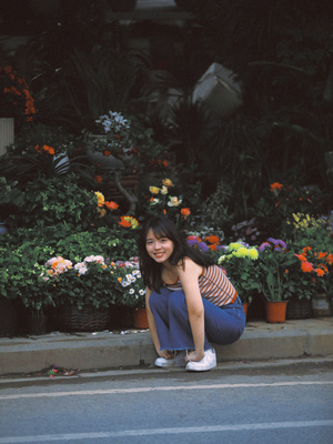 一位年轻女子跪在花店前的人行道上 一个女孩坐在路边。