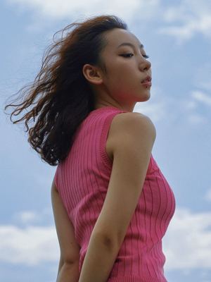 一位穿着粉红色连衣裙的年轻女子抬头望向阴沉的蓝色天空