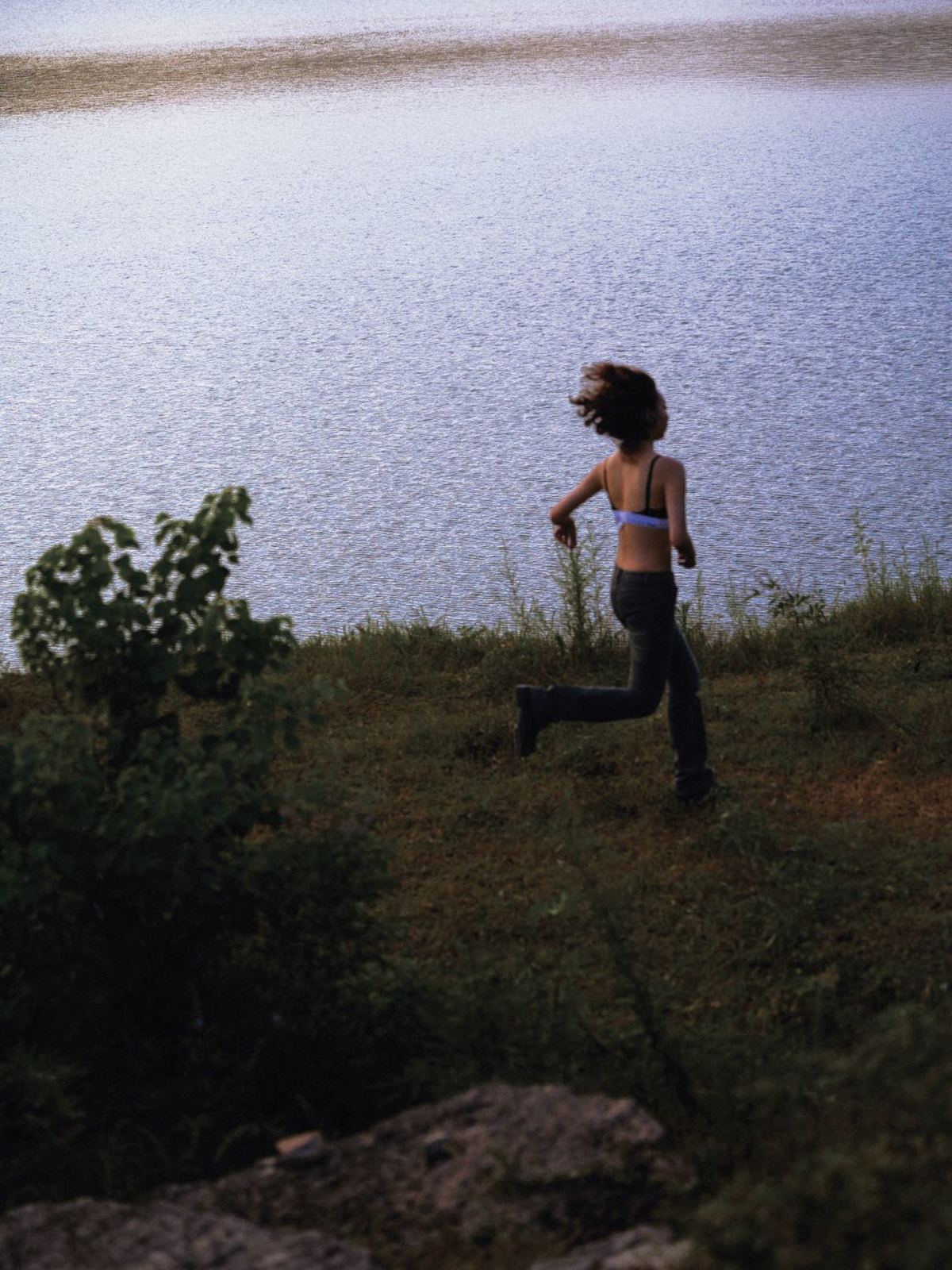 一位年轻女子在靠近水域的山坡上奔跑