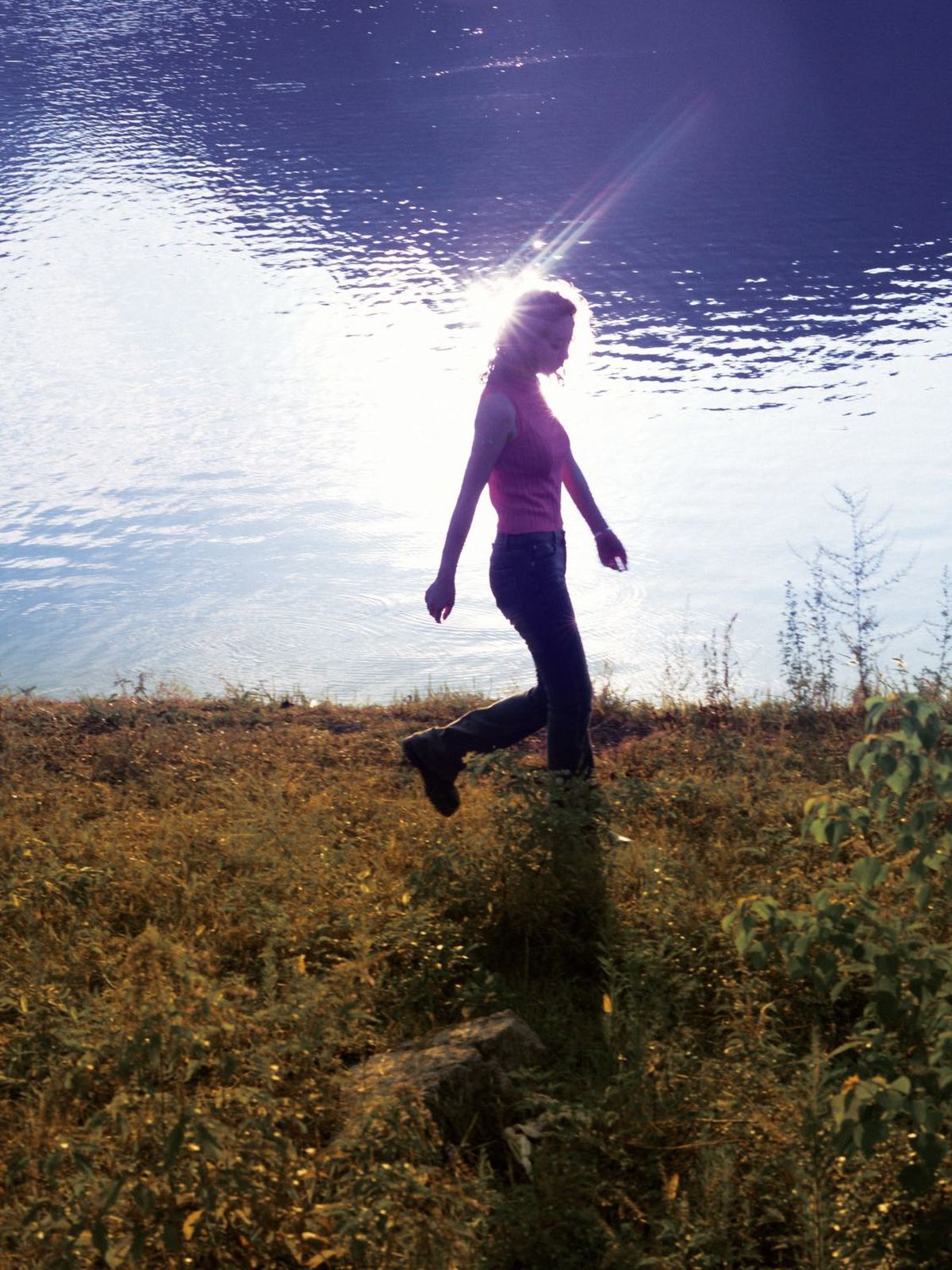 一位年轻女子在湖边跑过 太阳在她的身后 一个女孩在她前面跑过。