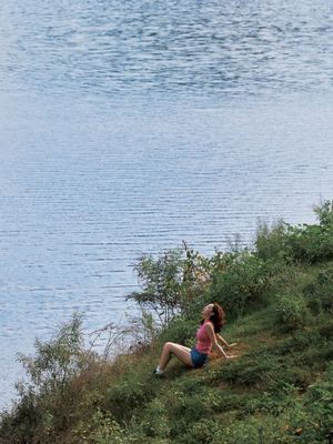 一位年轻女子坐在湖边或水体的草地上